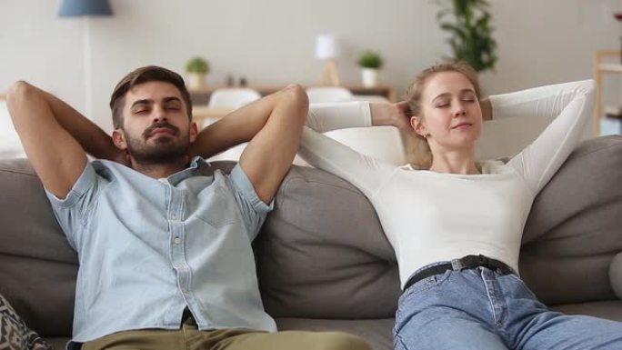平静的年轻夫妇在舒适的沙发上放松