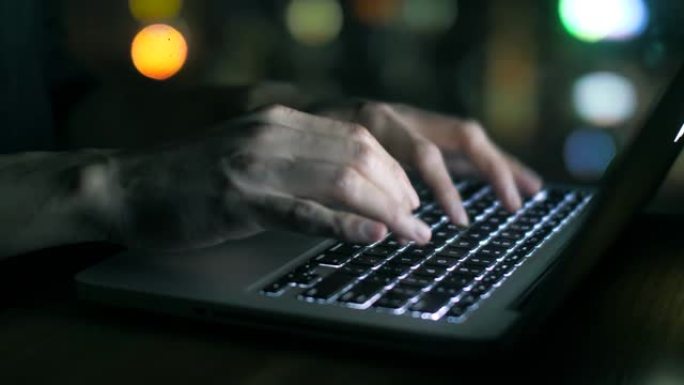 男人的手在晚上在笔记本电脑上打字