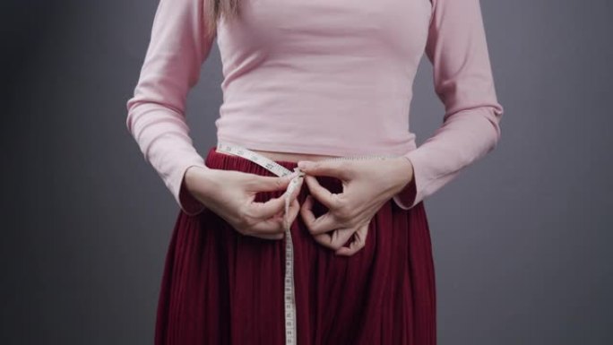 迷人的亚洲女性或时髦女性测量她的腰部。女工作女孩用卷尺检查她的腹部大小。拥有医疗保健或时尚减肥概念的