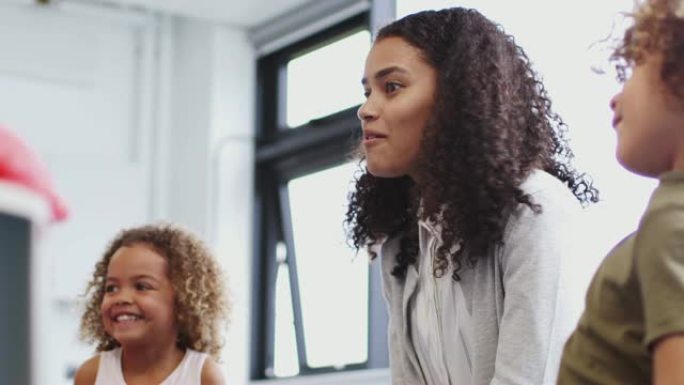 年轻的女教师在教室里与幼儿学校的孩子交谈，低角度，特写