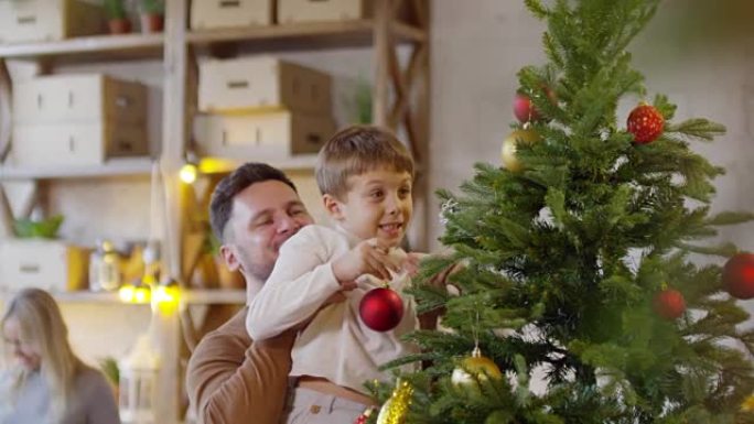 爸爸在装饰圣诞树时抱着孩子