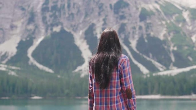 一个美丽的女人在木凳上徒步旅行。这个女人对周围的风景感到高兴和热情，并钦佩他。