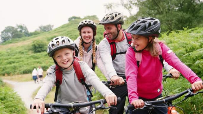 家庭野营旅行期间坐在山地自行车上的父母和孩子，特写，湖区，英国