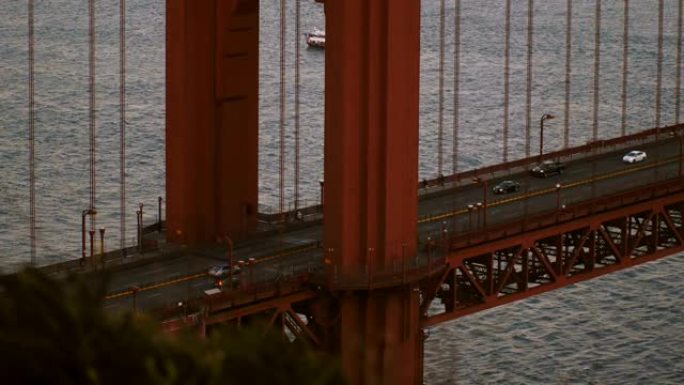 特写镜头在旧金山加州雄伟的日落金门桥柱和汽车交通上倾斜。