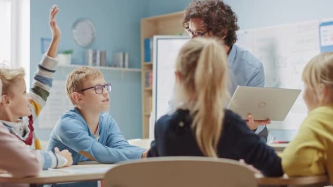 小学物理老师使用交互式数字平板电脑向聪明的孩子的教室展示可再生能源和风力涡轮机的工作原理。科学课，孩