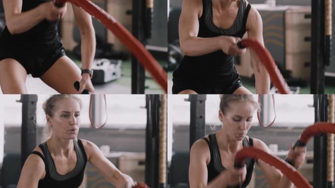 特写慢动作，年轻美丽的运动金发女子在大型健身房用战斗绳锻炼。