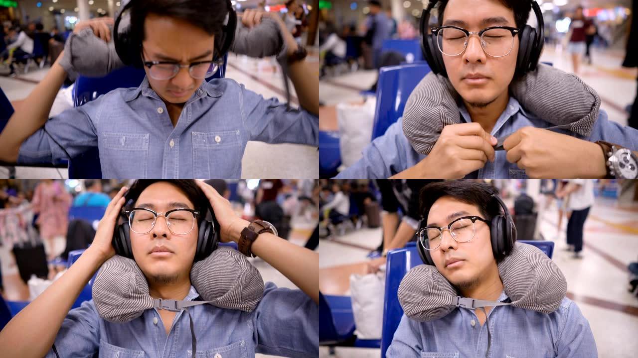 亚洲男子使用旅行颈枕在机场用耳机小睡