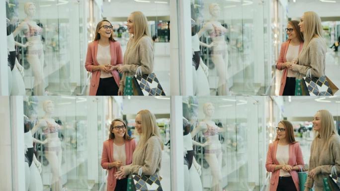 几个女孩在购物中心聊天，讨论新的内衣系列，这些内衣指向人体模型上的服装并聊天。销售，快乐的顾客和人的