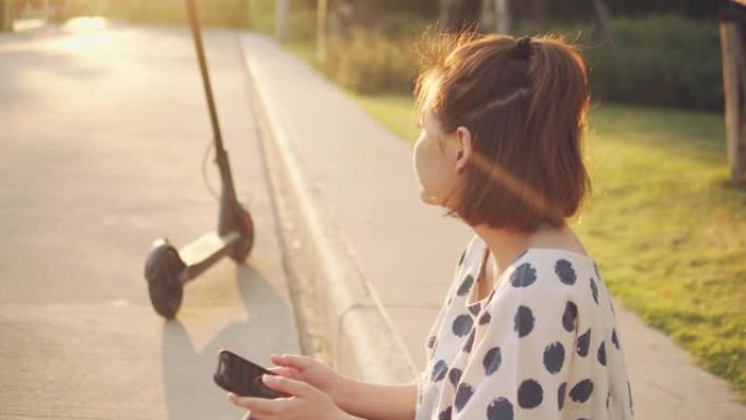 亚洲旅游女子使用手机通过app解锁电动滑板车