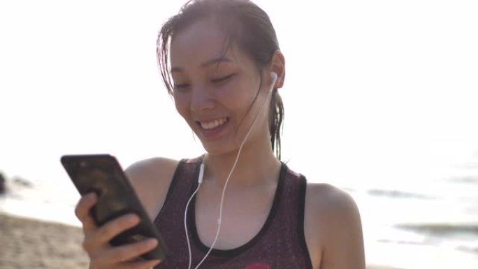 亚洲运动女性使用带耳机的智能手机