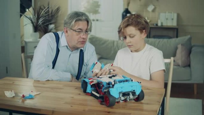 祖父和他的孙子正在组装一辆玩具车