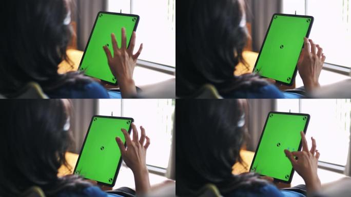 女人使用绿屏数字平板电脑和家庭。