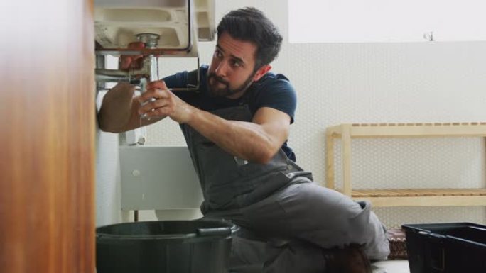 男性水管工致力于修复家庭浴室中漏水的水槽