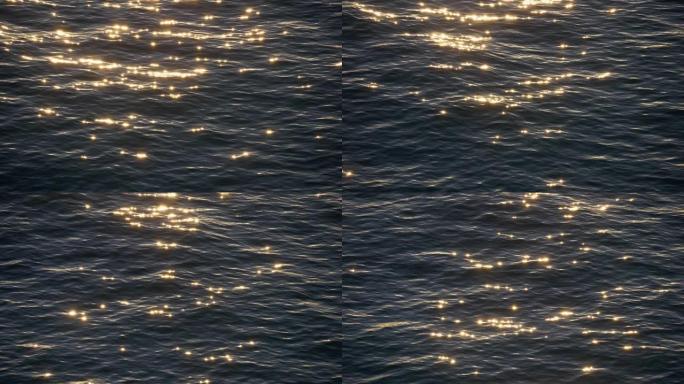 闪耀着金色光芒的海水表面。太阳在日落时在水中反射。慢动作镜头