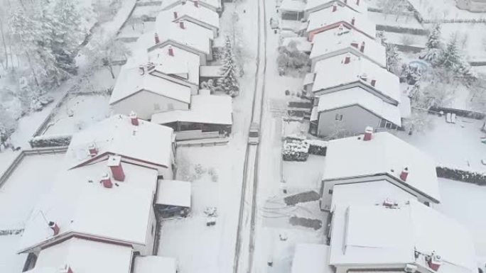 空中: 汽车驶过雪谷郊区，经过积雪覆盖的排屋