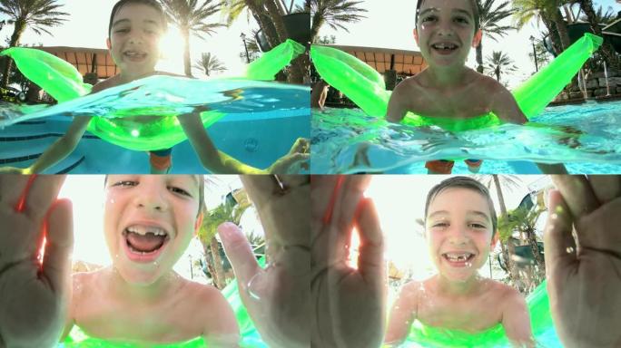 泳池筏上的男孩大笑，游到相机镜头前