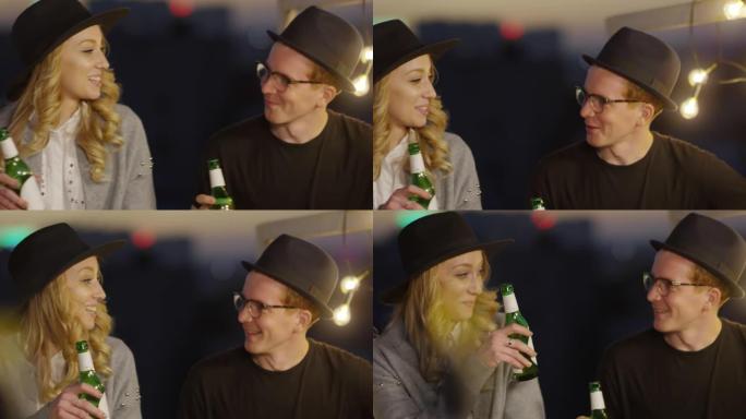 年轻夫妇在晚上的屋顶聚会上聊天和喝啤酒
