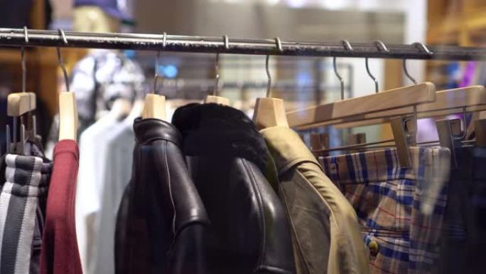 4k镜头在百货商店，购物中心和服装概念的时尚服装店的衣架和衣架上悬挂衣架和栏杆的场景