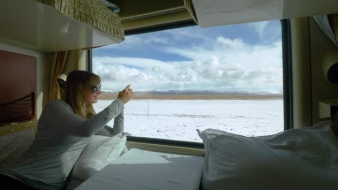 特写: 女人在火车上拍摄白雪皑皑的藏族风景。