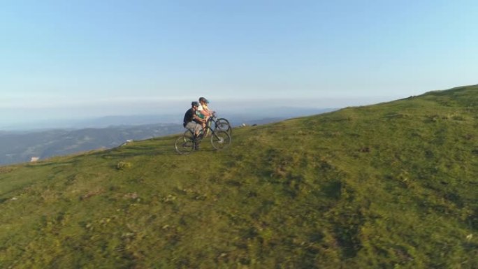 空中: 在一个阳光明媚的下午，朋友们在草木山上骑电动自行车。