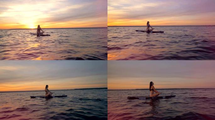 一个晚上在水上沉思的女孩。女冲浪者坐在海边的板上，练习瑜伽。