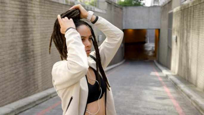 年轻的非洲裔美国妇女在城市里绑她的updo 4k的侧视图