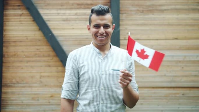 迷人的混血男子手持加拿大国旗在户外微笑的肖像
