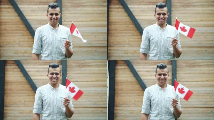 迷人的混血男子手持加拿大国旗在户外微笑的肖像