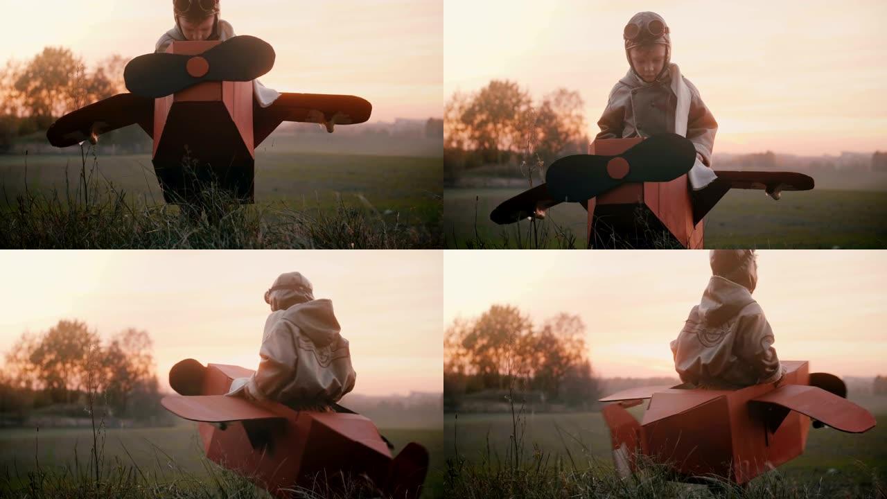 快乐的小飞行员男孩坐在有趣的纸板飞机上，在日落秋天的野外玩耍，享受有趣的慢动作。
