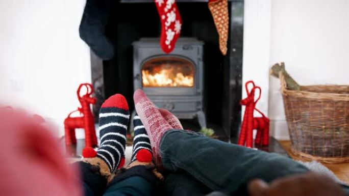 低矮的情侣穿着圣诞袜在壁炉前放松，细节