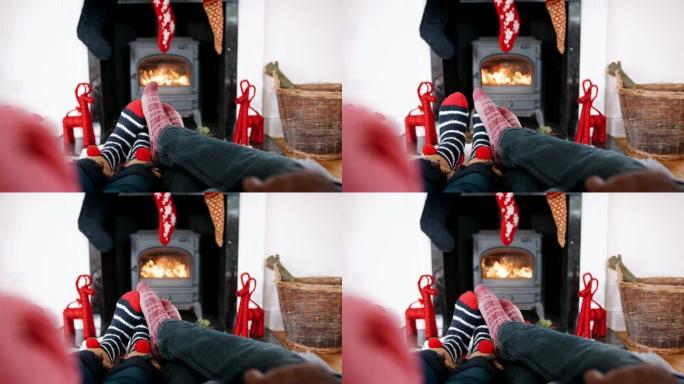 低矮的情侣穿着圣诞袜在壁炉前放松，细节