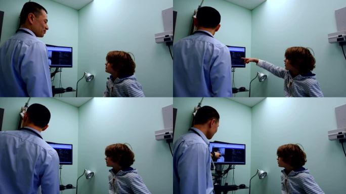年轻的亚洲男医生在电脑屏幕4k上向高加索男孩病人展示x光的侧视图