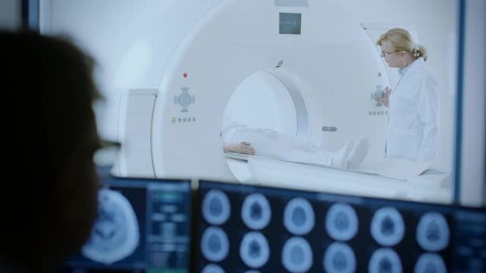 在医学实验室中，患者在放射科医生的监督下进行MRI或ct扫描过程，在控制室医生监视程序并监视脑部扫描