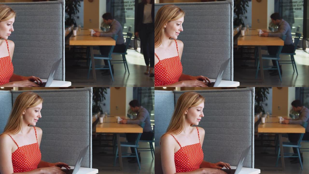年轻的女商人在现代办公室工作空间的隔间里使用笔记本电脑