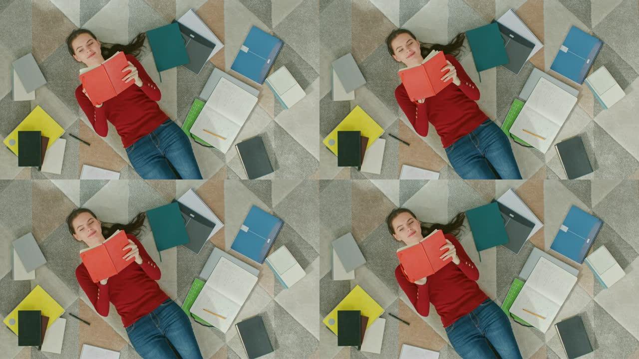 穿着红色外套和蓝色牛仔裤的年轻女孩躺在地板上，读笔记本。她笑着笑。舒适的客厅配有现代室内地毯、工作簿