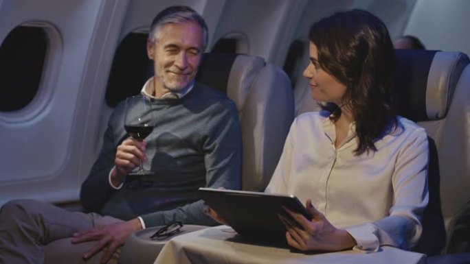 在飞机上使用数字平板电脑的女商人