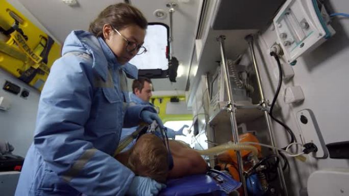 护理人员在救护车上给病人戴上氧气面罩