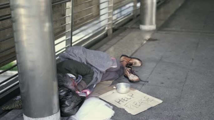 向下倾斜: 无家可归者睡在人行道上。