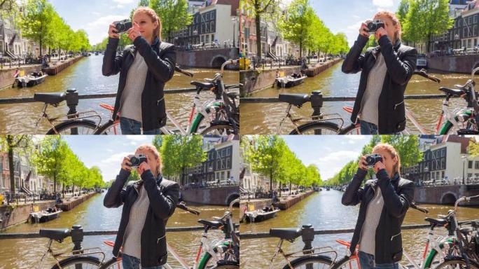 在阿姆斯特丹旅行的女游客，在美丽的晴天用老式模拟相机拍摄运河照片
