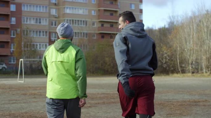 两名男运动员在足球场上散步聊天