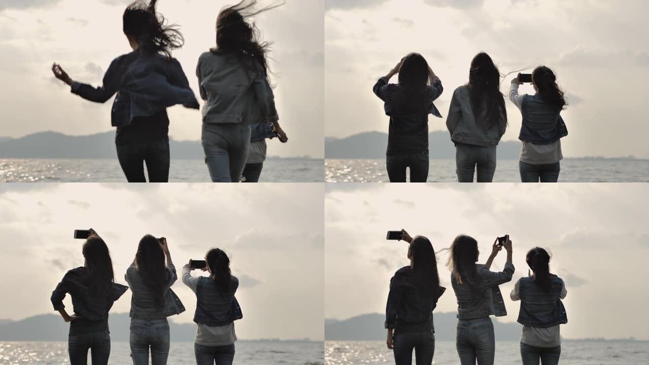 剪影组的朋友在湖里奔跑，用智能手机拍照。兴奋的组年轻女子在旅途中享受大自然。旅行生活方式冒险假期，露