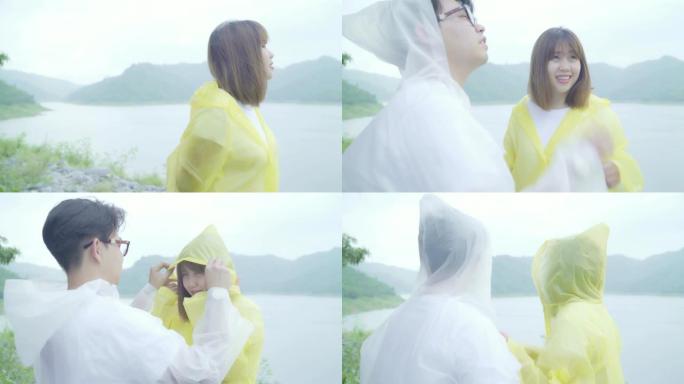 年轻的亚洲甜蜜夫妇穿着雨衣站在湖边，享受浪漫的雨水时光，感到快乐。生活方式夫妇在雨天享受和放松。