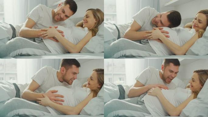幸福的年轻夫妇在床上拥抱在一起，年轻的女人怀孕了，有爱心的伴侣俯身听着婴儿的动作，肚子里的心跳。家庭