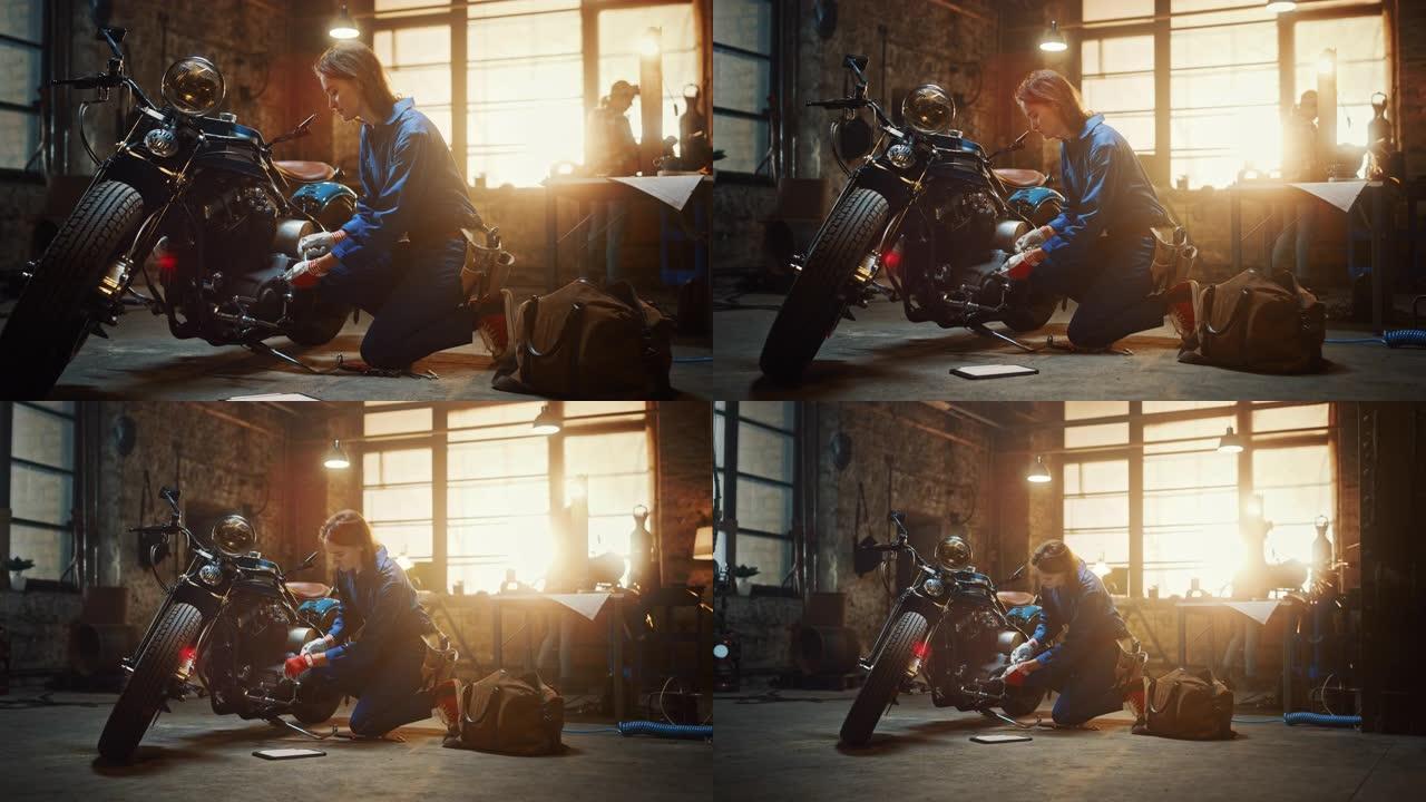 年轻漂亮的女机械师正在修理一辆定制的摩托车。穿着蓝色连体裤的天才女孩。她使用棘轮扳手并检查平板电脑以