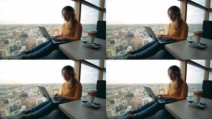 一位女士正在全景窗户旁边的笔记本电脑上工作