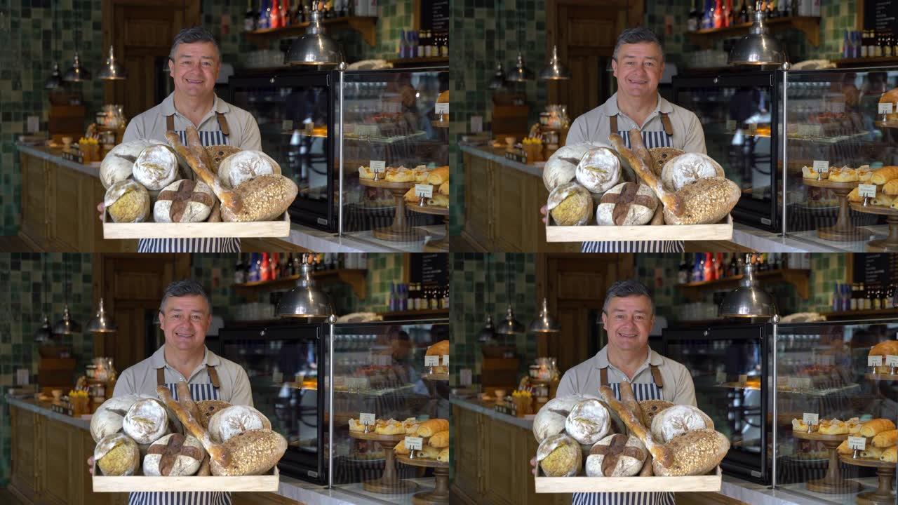 一家面包店的快乐成熟企业主在对着镜头微笑时展示了一个装有面包的篮子