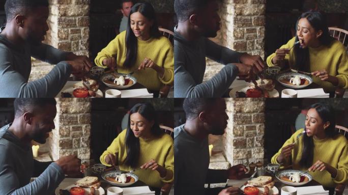 夫妇坐在传统英国度假酒店的餐桌旁，吃煮熟的早餐和水果煎饼