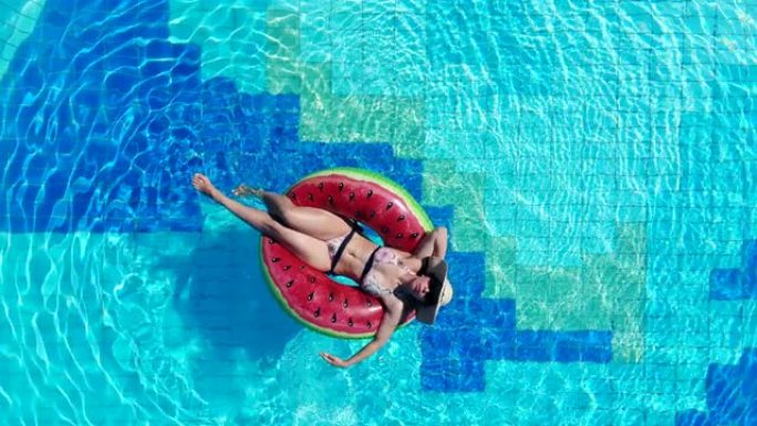 一名妇女在游泳池放松时漂浮在橡胶圈上。