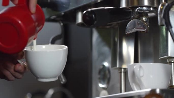 咖啡师将蒸牛奶倒入卡布奇诺咖啡的咖啡杯中