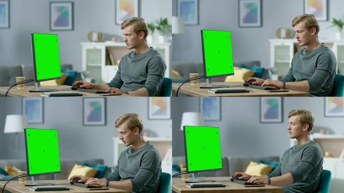 英俊的专注的年轻人坐在舒适的公寓里的办公桌旁，在绿色的模拟屏幕个人电脑上工作。
